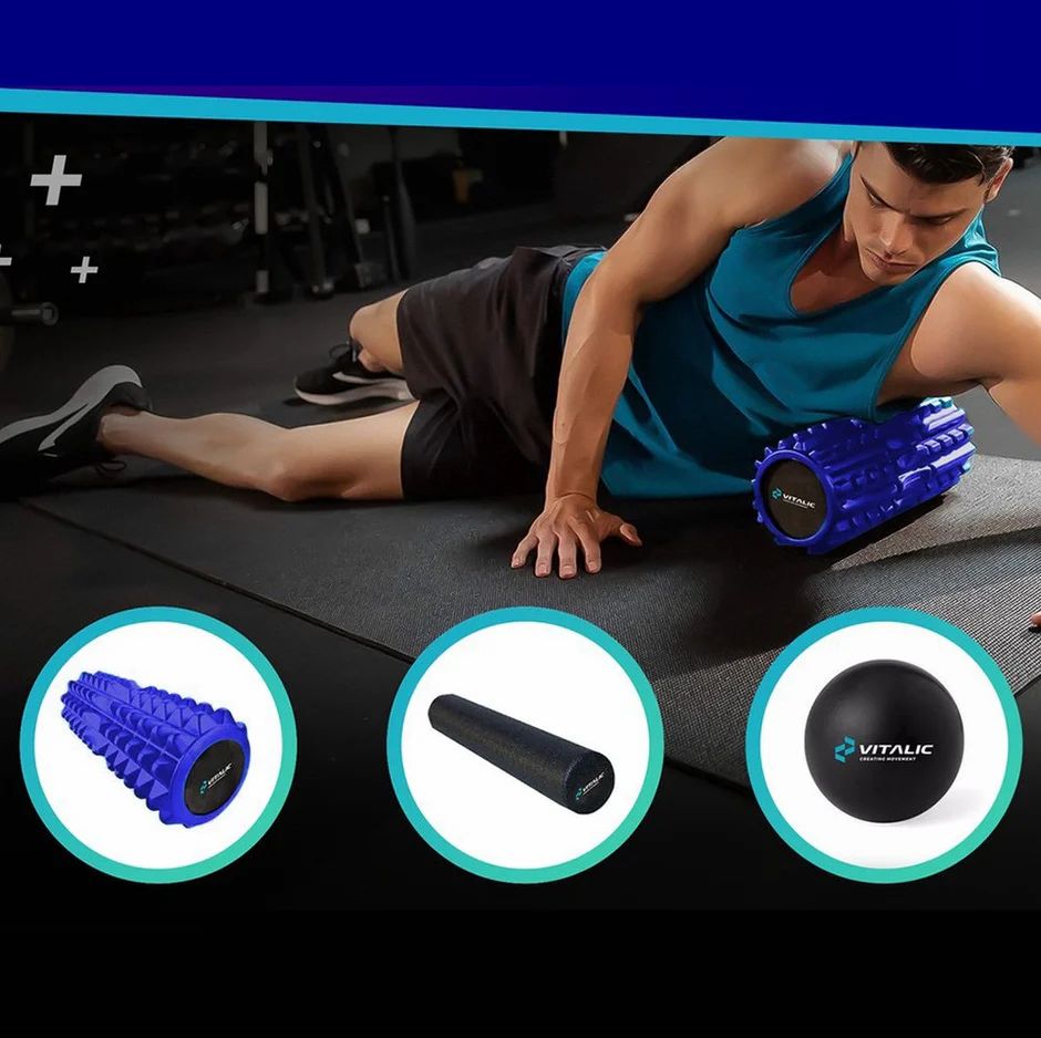Mann im Fitnessstudio nutzt blaue Faszienrolle für Beinmassage, daneben schwarze Rolle und Ball.