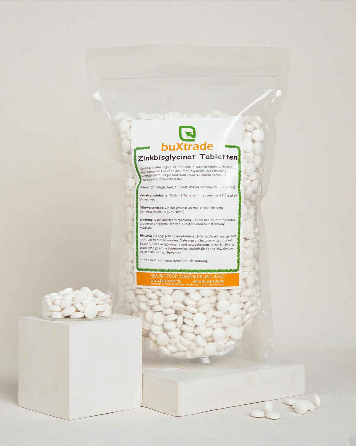 Bags of buXtrade Zinkbisglycinat Tabletten, a dietary supplement, with a glass of tablets.