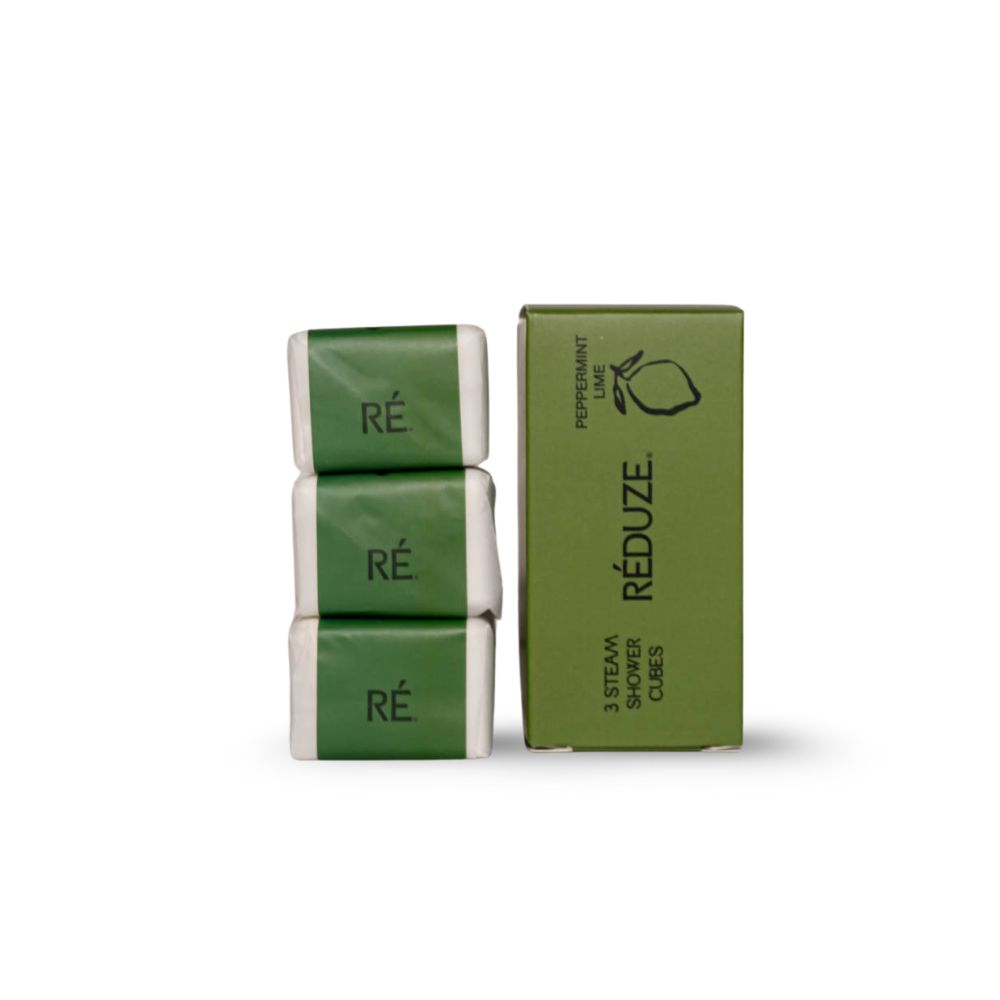 3 in Papier verpackte Duschwürfel neben einer grünen Schachtel. Aufschrift: RÉDUZE.