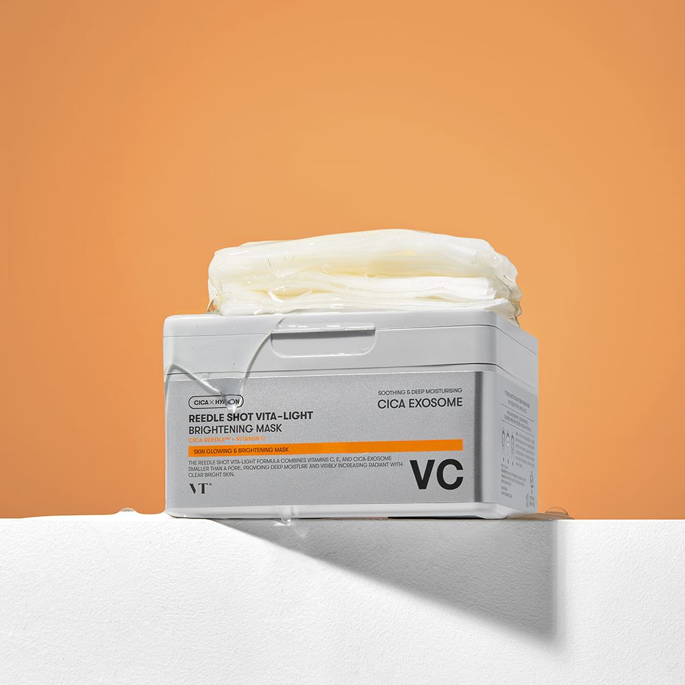 Graue Box mit Masken auf weißem Podest vor orangefarbenem Hintergrund. Aufschrift: Reedle Shot Vita-Light Brightening Mask. Marke: VT.