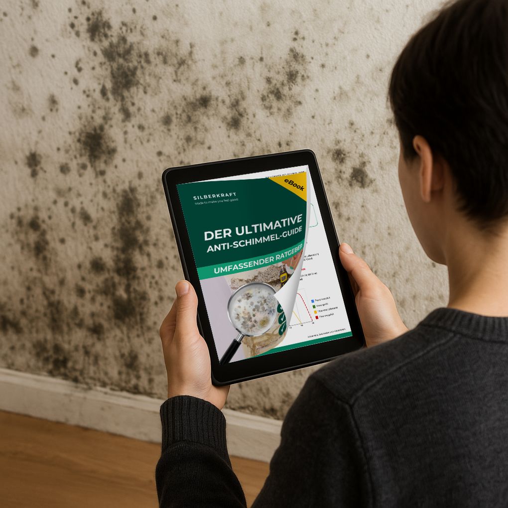 Person hält Tablet mit eBook-Cover. Titel: Der Ultimative Anti-Schimmel-Guide. Hintergrund: Schimmelbefall an Wand.