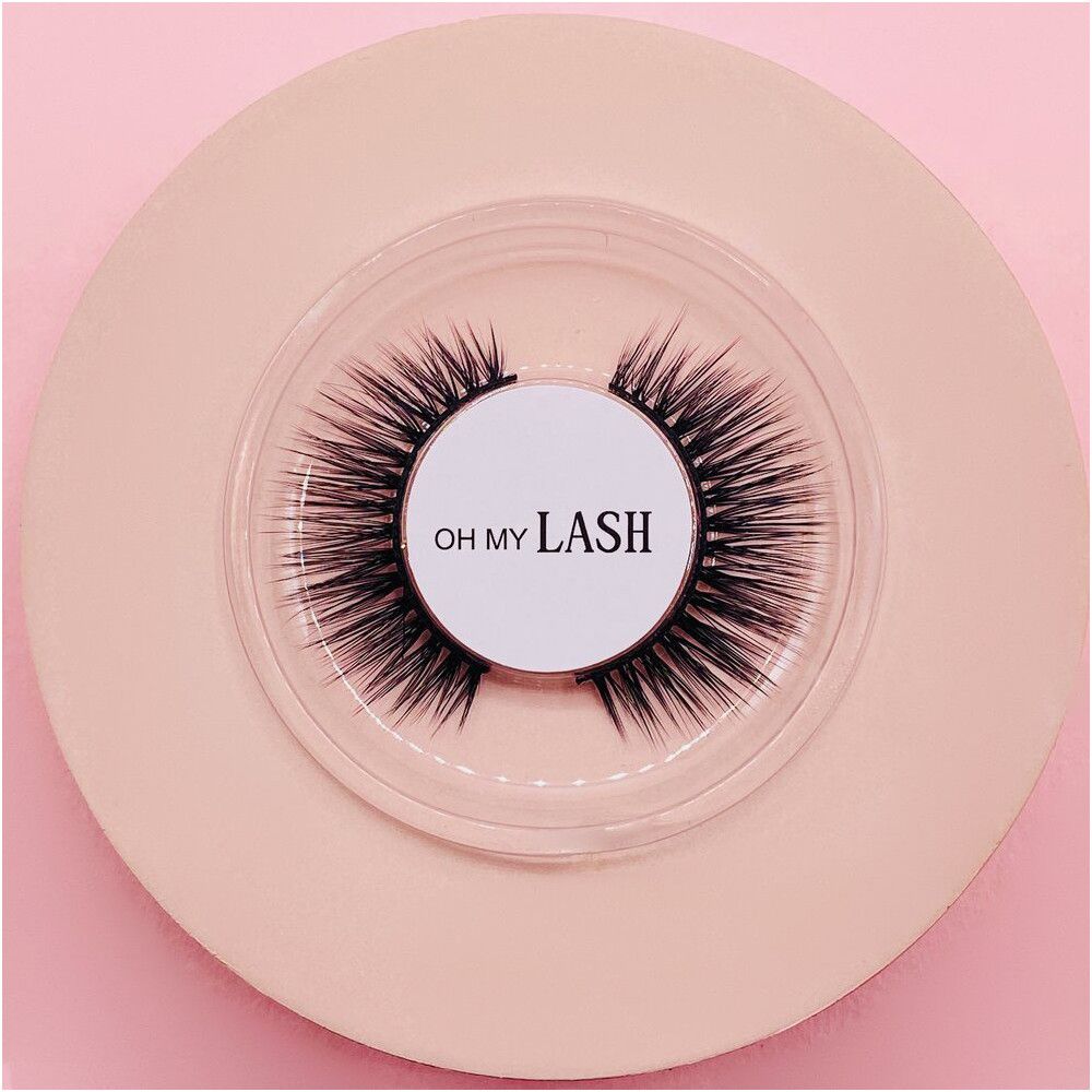 Falsche Wimpern in runder, transparenter Verpackung. Auf dem Etikett steht "OH MY LASH".