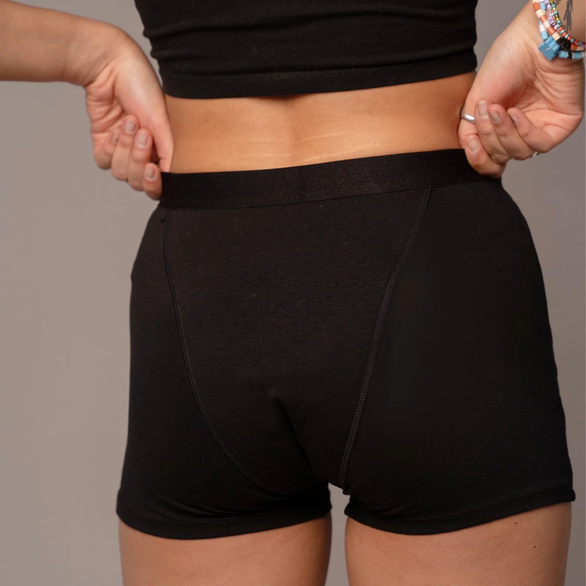 Rückansicht einer schwarzen, kurzen Unterhose. Elastischer Bund. Stoff bedeckt den Gesäßbereich.