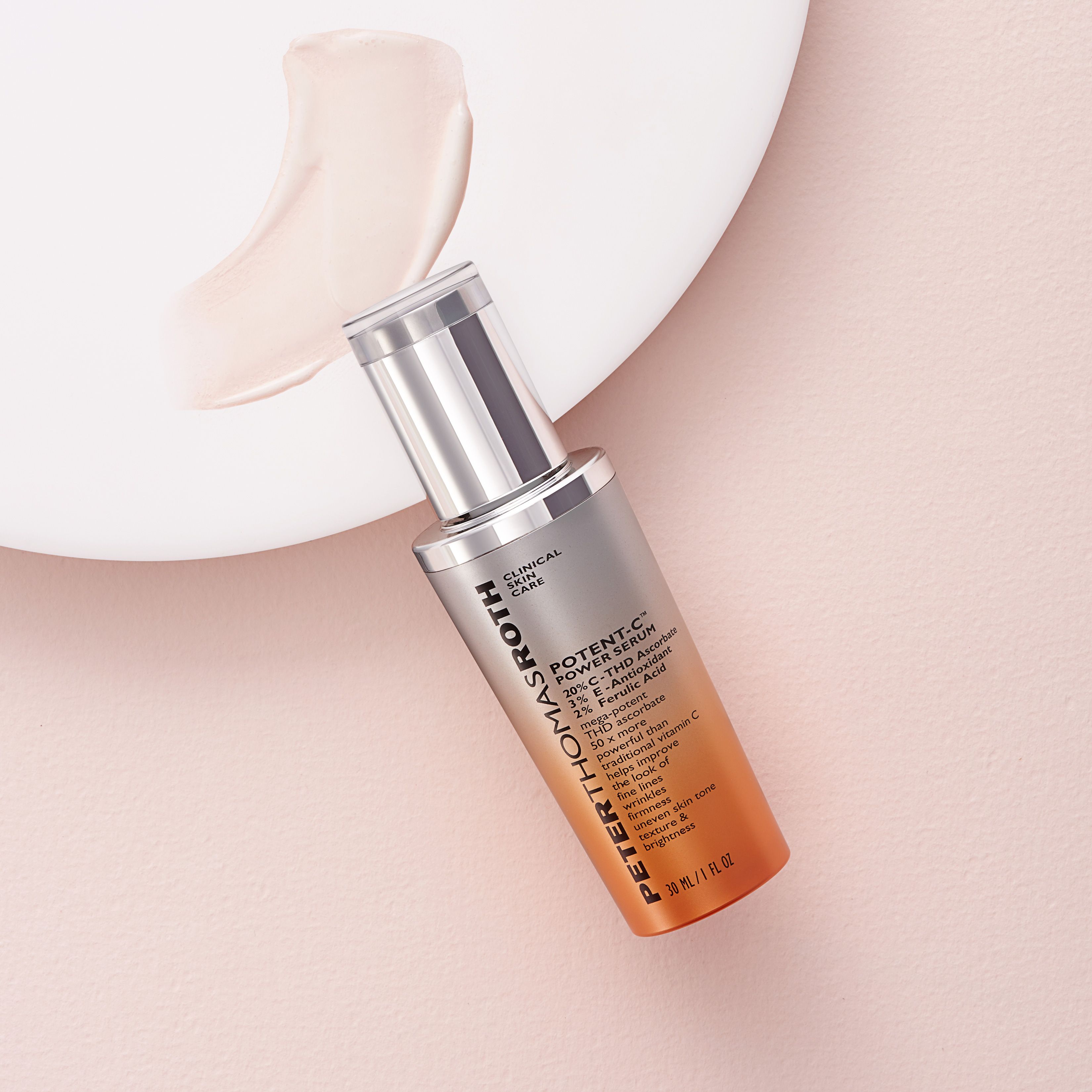 Serumflasche auf rosa Untergrund. Daneben ein Klecks Serum. Aufschrift: Potent-C Power Serum. Silberne Kappe und orangefarbener Farbverlauf.