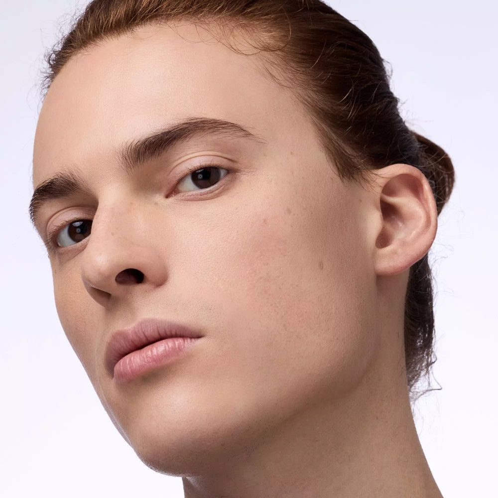 Porträt eines Mannes mit glatter Haut und hochgesteckten Haaren. Der Blick ist nach oben gerichtet.