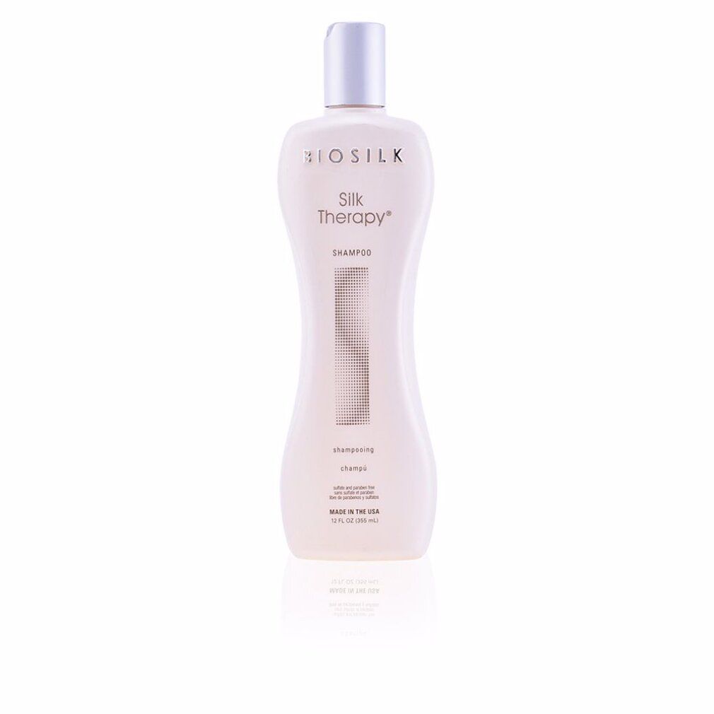 Biosilk Silk Therapy Shampoo Flasche. Weißes, tailliertes Design mit silbernem Deckel. Text: Shampoo, Made in the USA.