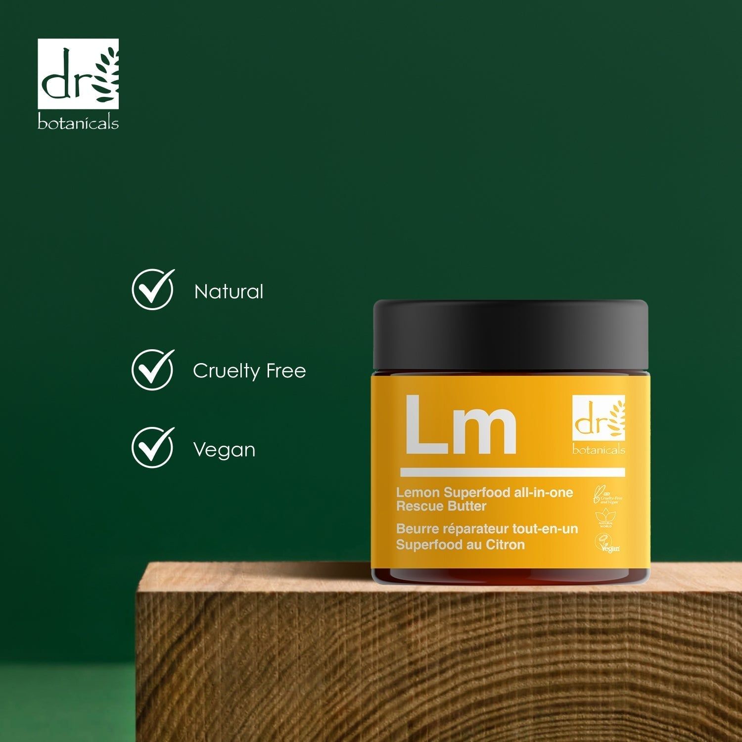 Gelber Tiegel mit "Lm" und "dr botanicals" auf Holzblock. Text: Lemon Superfood all-in-one Rescue Butter. Vegan, Cruelty Free, Natural.