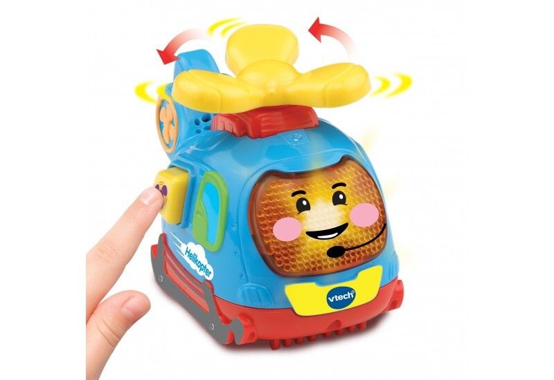 Blauer, roter und gelber Spielzeug-Helikopter. Ein Finger berührt einen Knopf. Vtech-Logo sichtbar.