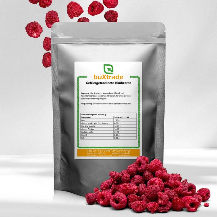 Silberfarbene Tüte mit Etikett. Gefriergetrocknete Himbeeren liegen davor und fallen von oben. Aufschrift: buXtrade Gefriergetrocknete Himbeeren.