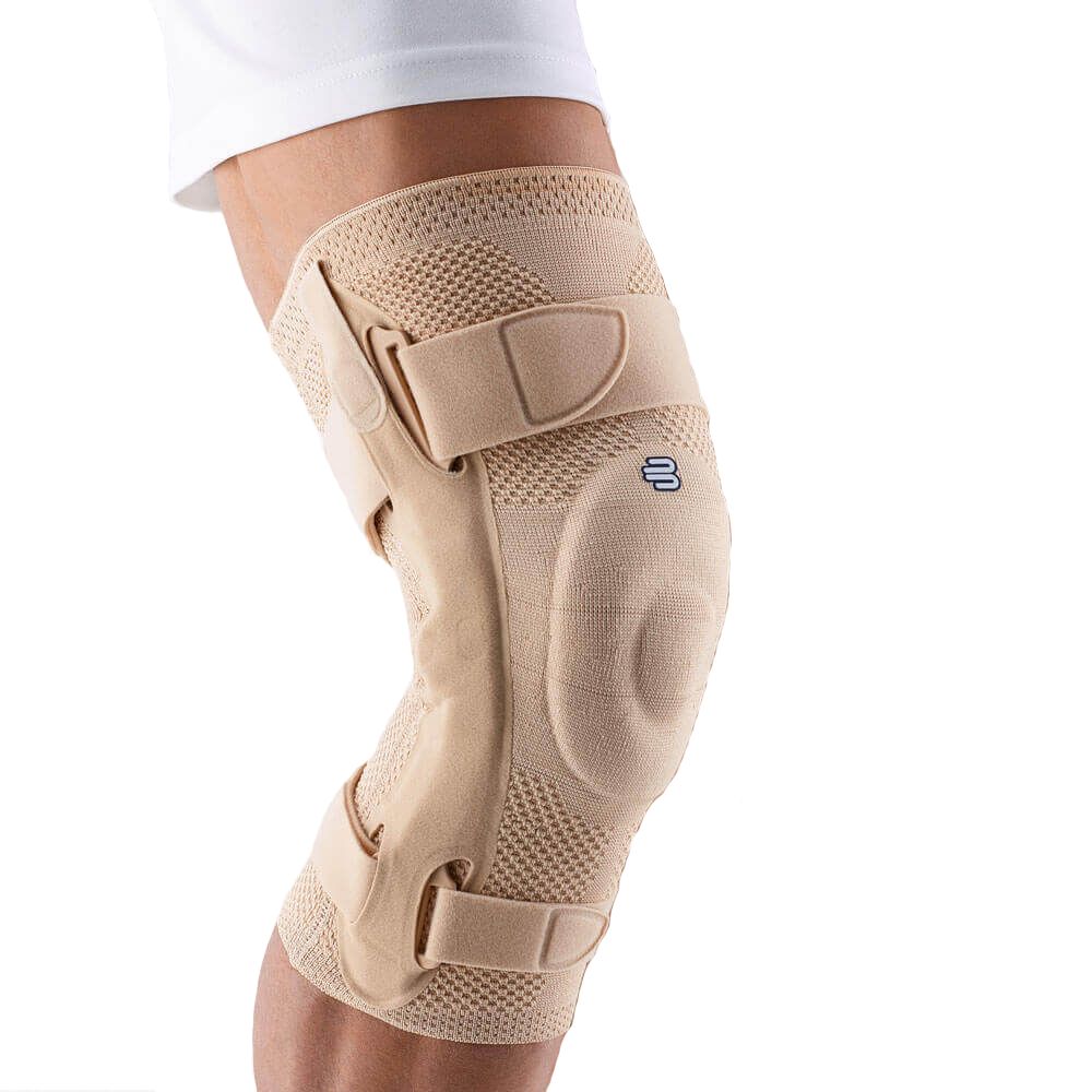 Beige Kniebandage mit Klettverschlüssen und seitlichen Verstärkungen. Das Produkt ist am Bein einer Person angebracht.