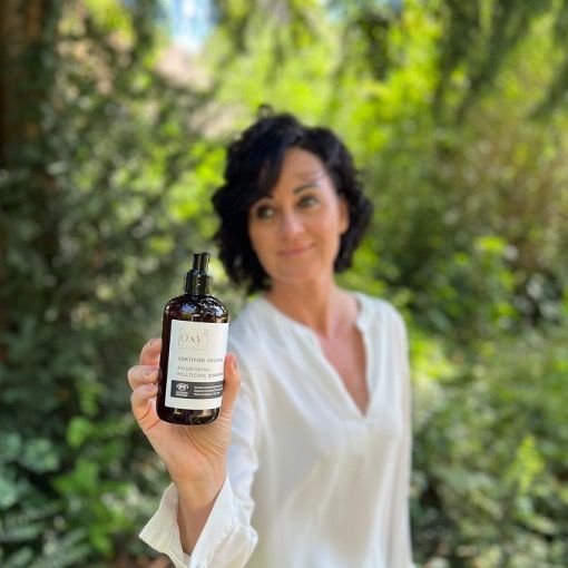 Eine Frau hält eine Shampoo-Flasche. Auf dem Etikett steht "oxy8" und "Nourishing Multicare Shampoo".