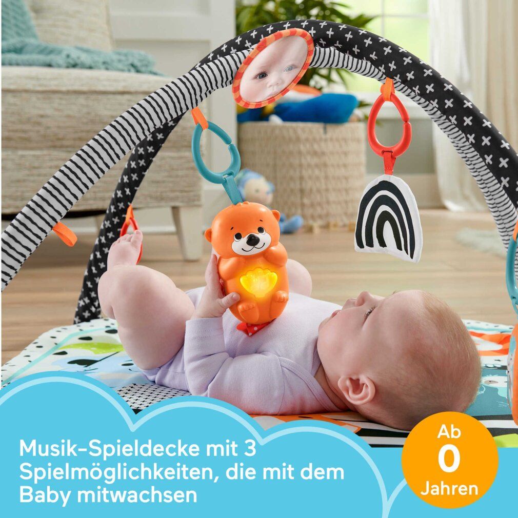 Baby liegt auf Spieldecke. Spielbogen mit Spielzeug. Text: Musik-Spieldecke mit 3 Spielmöglichkeiten, die mit dem Baby mitwachsen.