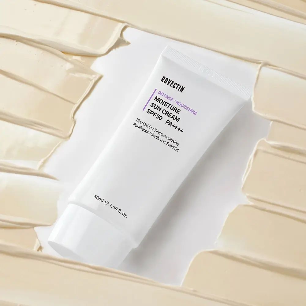 Weiße Tube mit lila Schriftzug. Produktname und SPF50+ PA++++ sind sichtbar. Umgeben von cremefarbenen Streifen.