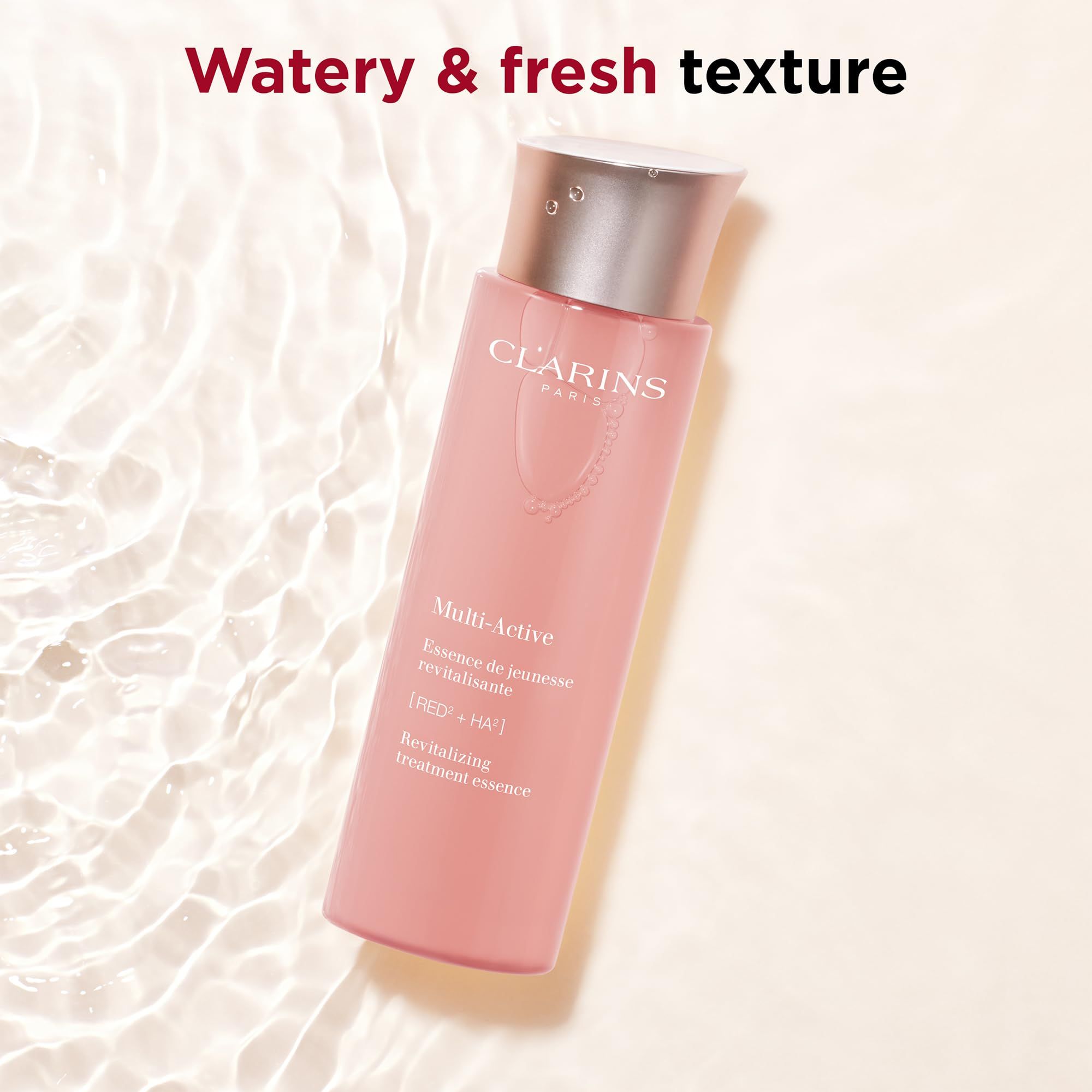 Clarins Multi-Active Essenz. Rosa Flasche mit silbernem Deckel. Text: Multi-Active, Revitalizing treatment essence. Hintergrund: Wasser.