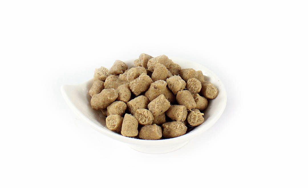 Hundefutter-Snacks in einer weißen Schale. Die Snacks sind hellbraun und haben eine unregelmäßige Form.