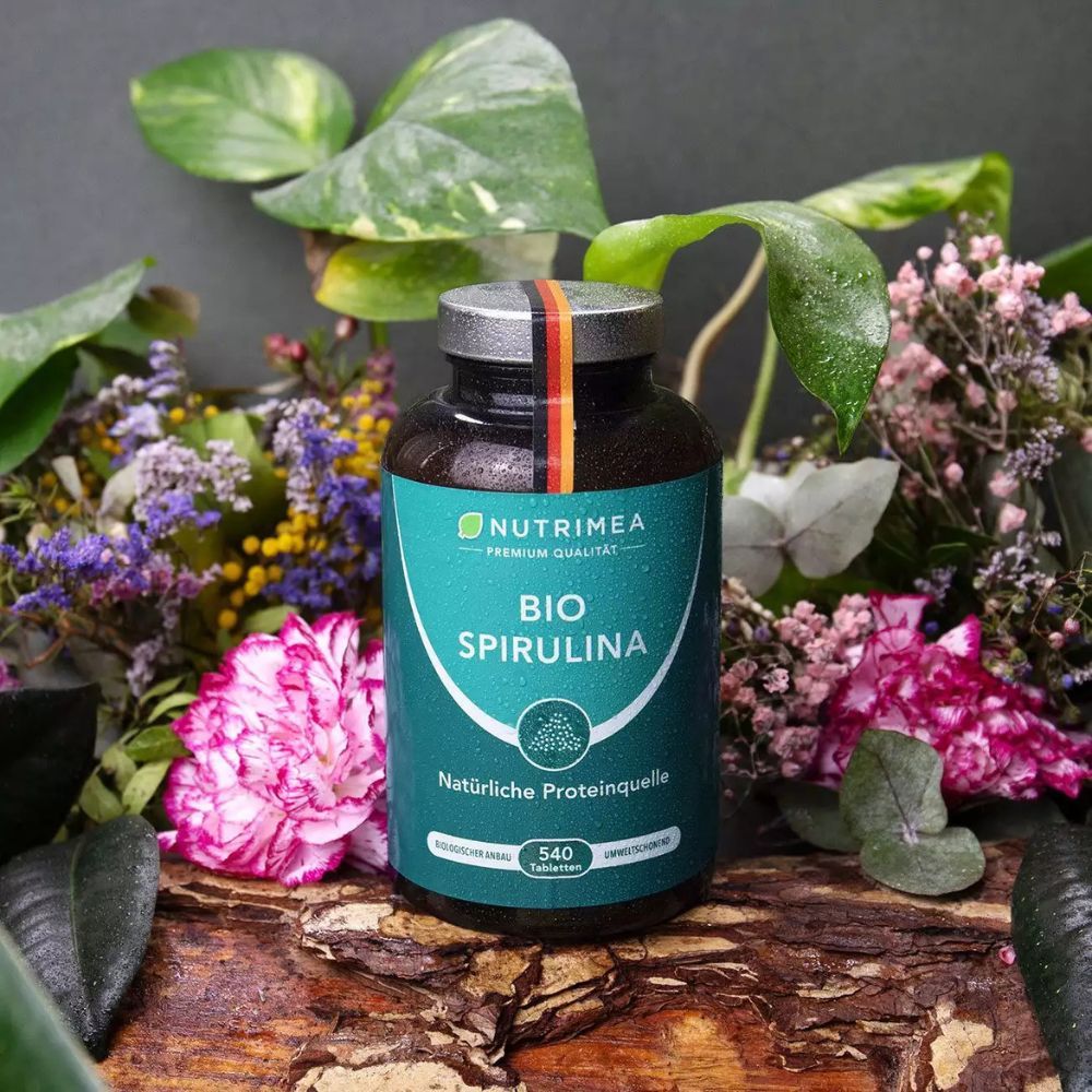 Dunkle Flasche mit grüner Aufschrift BIO SPIRULINA. 540 Tabletten. Natürliche Proteinquelle. Mit deutschem Fähnchen.
