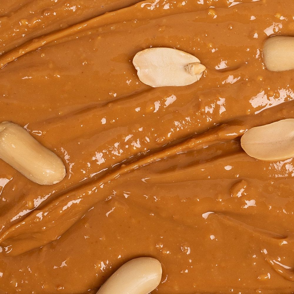 Nahaufnahme von Erdnussbutter Crunchy mit Erdnüssen. Einige Erdnüsse sind sichtbar.