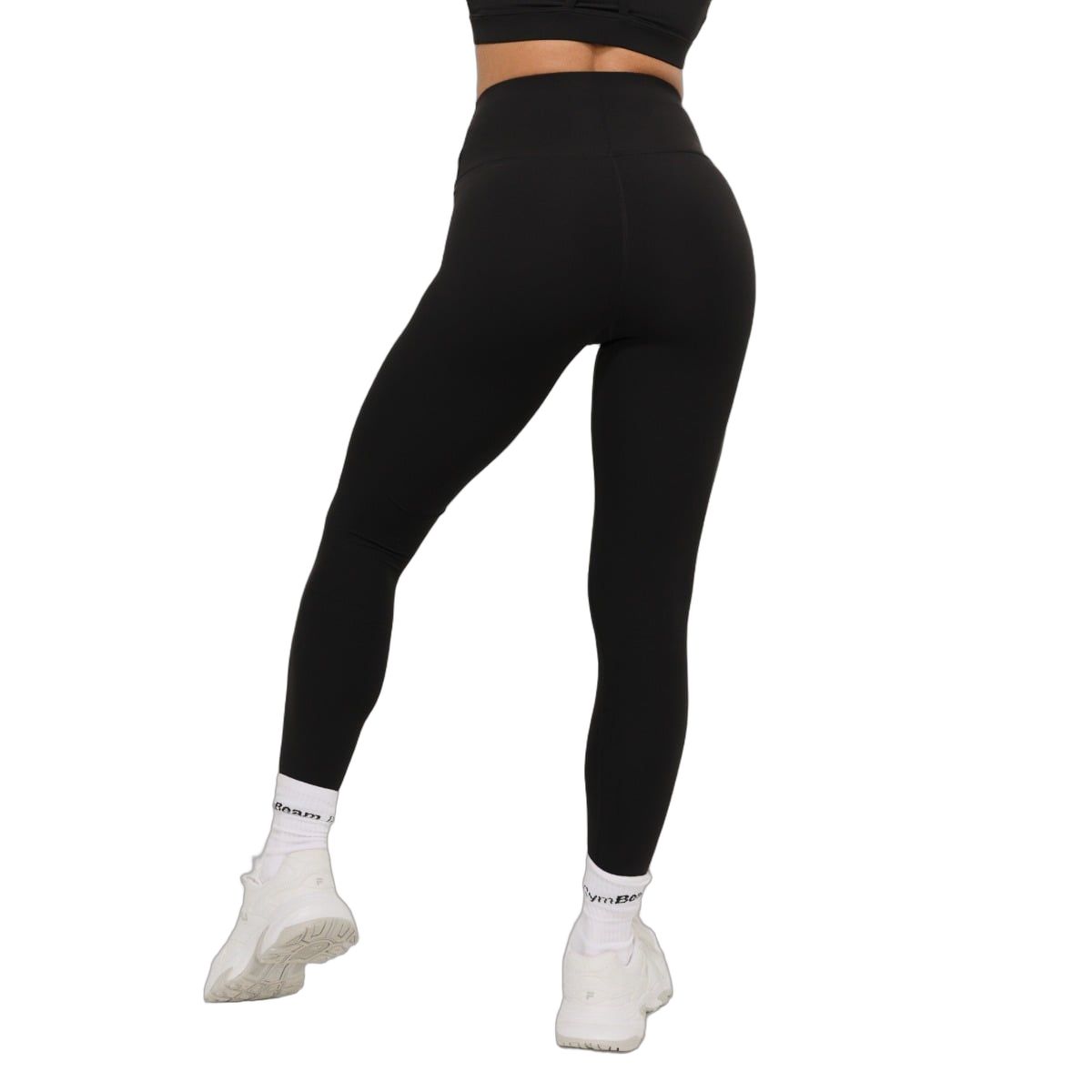 Rückansicht einer Frau in schwarzen Leggings mit hohem Bund und weißen Socken.