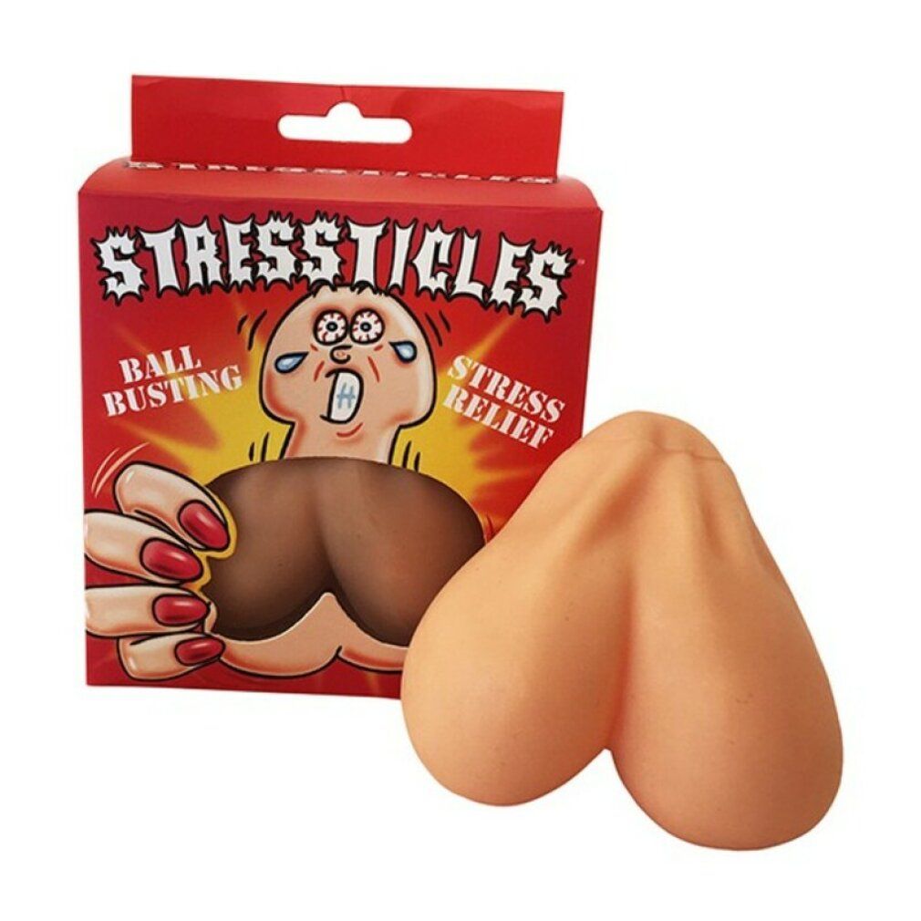 Beige Stressticles neben roter Verpackung. Aufschrift: STRESSTICLES, BALL BUSTING, STRESS RELIEF. Produkt aus Gummi.