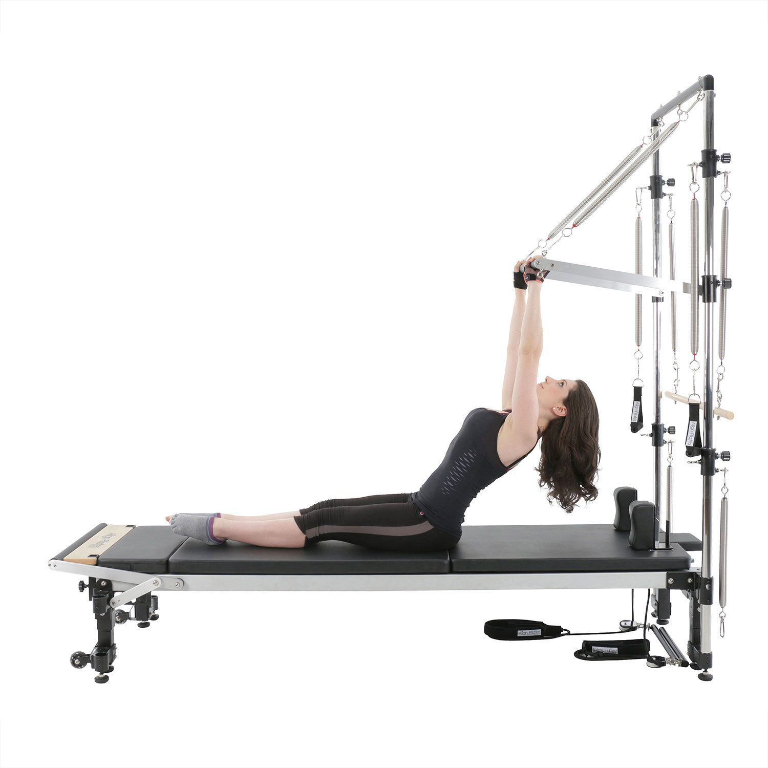Pilates-Reformer mit Half Cadillac. Eine Person liegt auf dem Reformer und trainiert. Blick von der Seite.