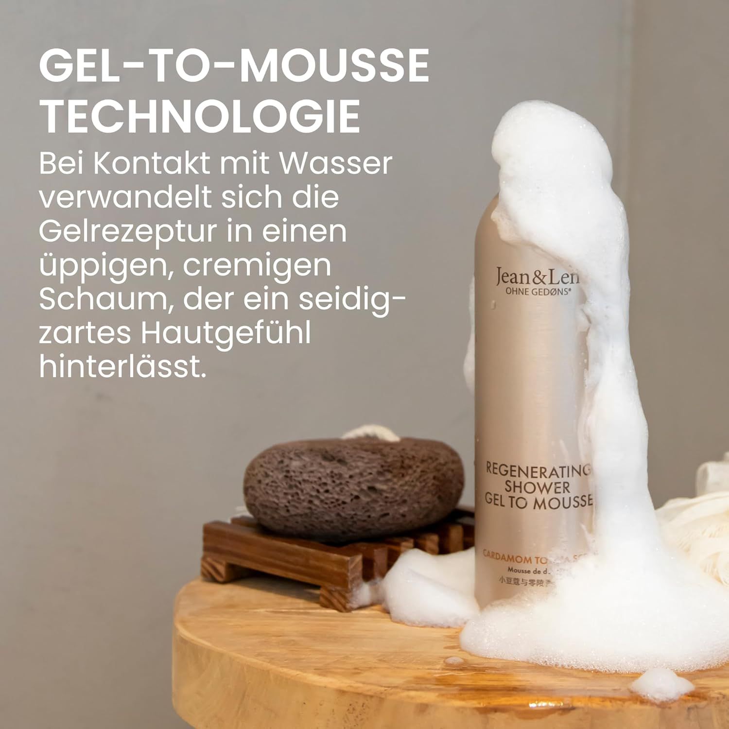 Beige Flasche mit weißem Pumpkopf und Schaum. Aufschrift: Jean & Len, Regenerating Shower Gel to Mousse. Neben Holzbrett und Stein.