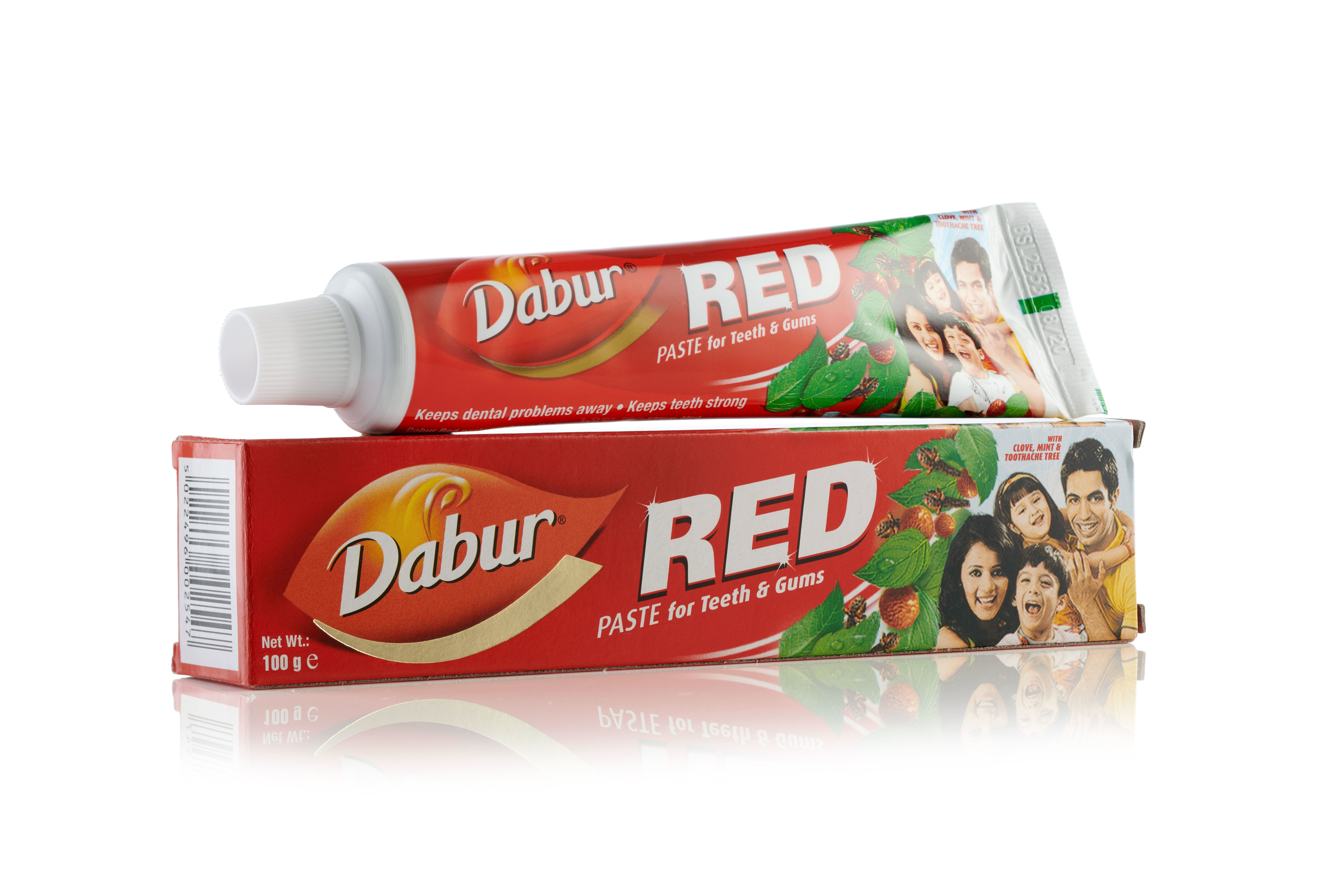 Dabur Red Zahnpasta-Tube liegt auf ihrer roten Verpackung. Beide zeigen ein Familienbild.