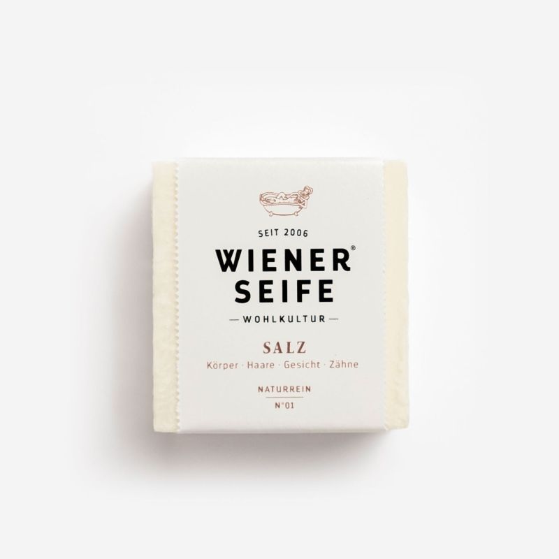 Quadratische Seife mit Papierverpackung. Aufdruck: Wiener Seife, Salz, N°01. Text: Körper, Haare, Gesicht, Zähne.
