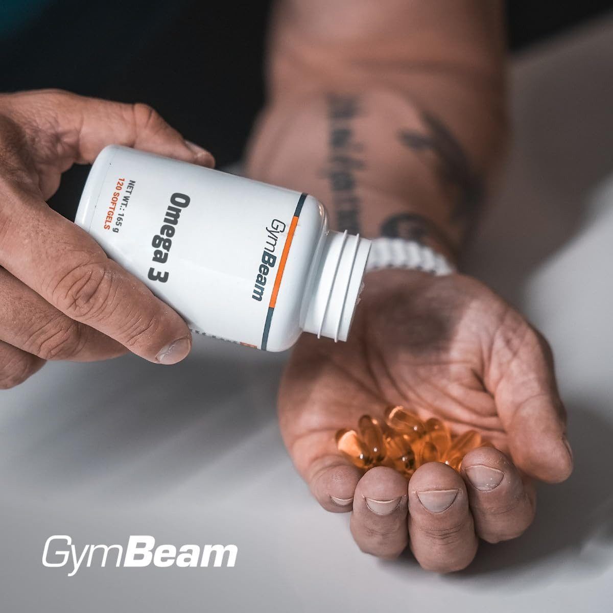 Eine Hand schüttet GymBeam Omega 3 Kapseln aus einem Behälter in die andere Hand.