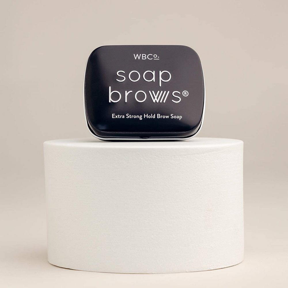 Schwarze Dose mit Schriftzug 'soap brows' auf weißem Podest.