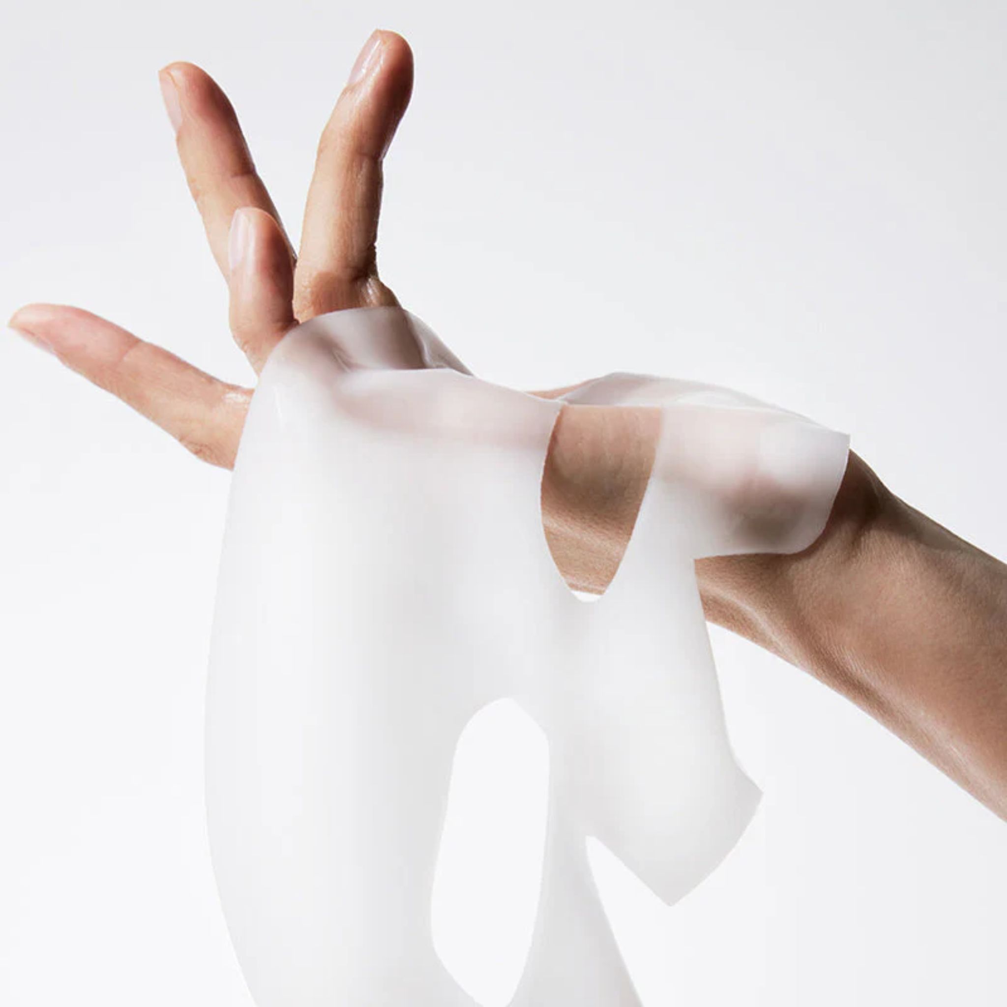 Hände halten eine transparente Gesichtsmaske. Die Maske hat Aussparungen für Augen, Nase und Mund. Sie ist aus einem weichen Material.