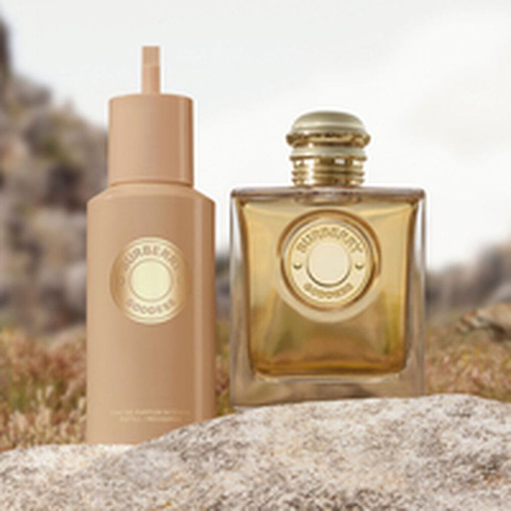 Zwei Parfumprodukte auf einer steinigen Oberfläche. Links eine Lotion, rechts ein Flakon. Beide mit Logo.