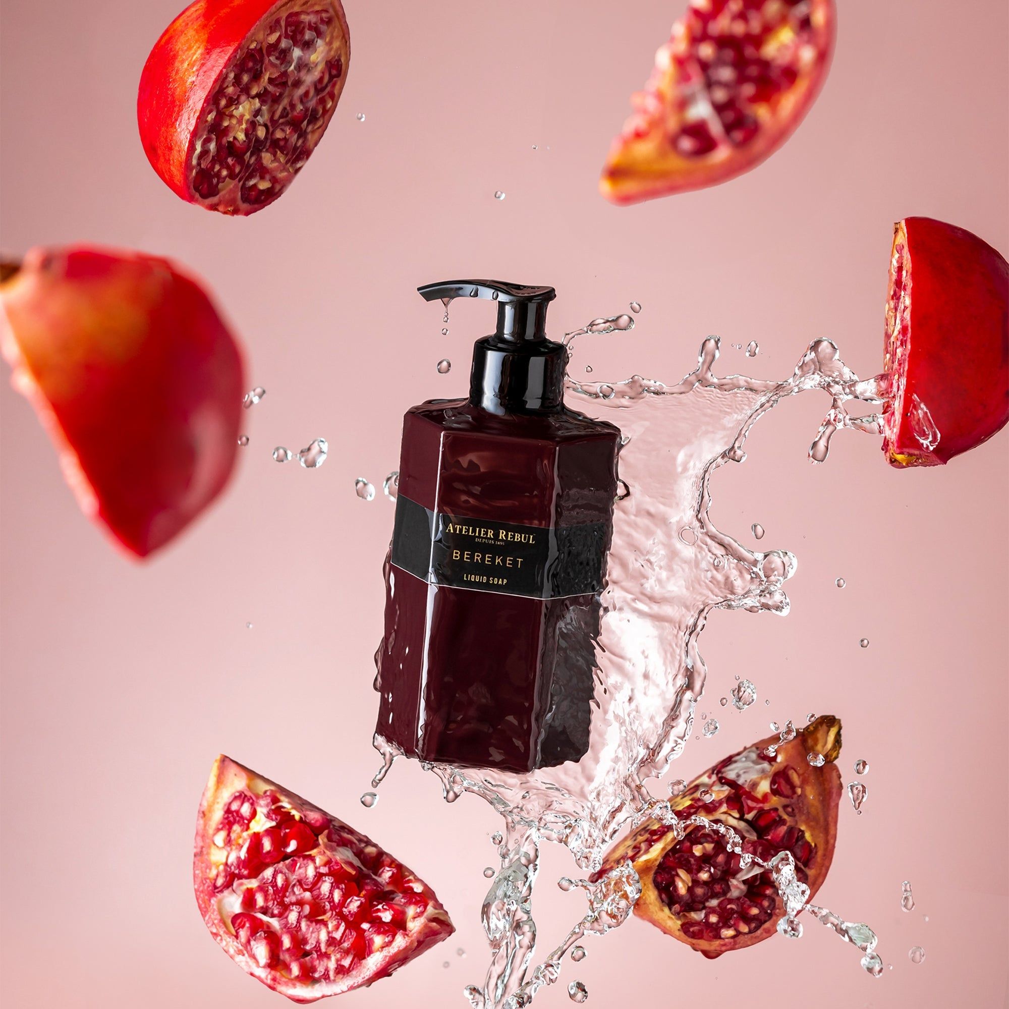 Bordeauxfarbene Flüssigseife mit schwarzem Pumpkopf. Granatapfelstücke und Wasserspritzer umgeben die Flasche. Aufschrift: Atelier Rebul Bereket.