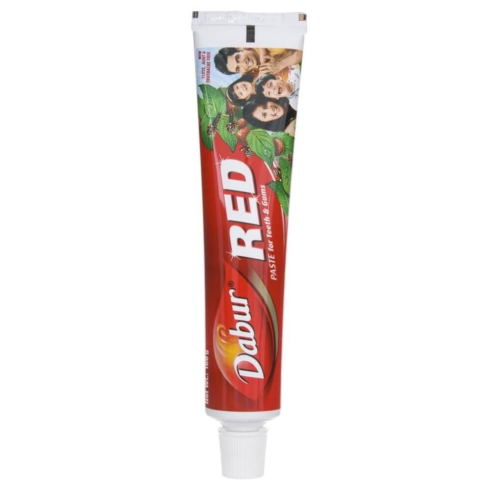 Dabur Red Zahnpasta-Tube mit rotem Design und Familienbild auf der Vorderseite.