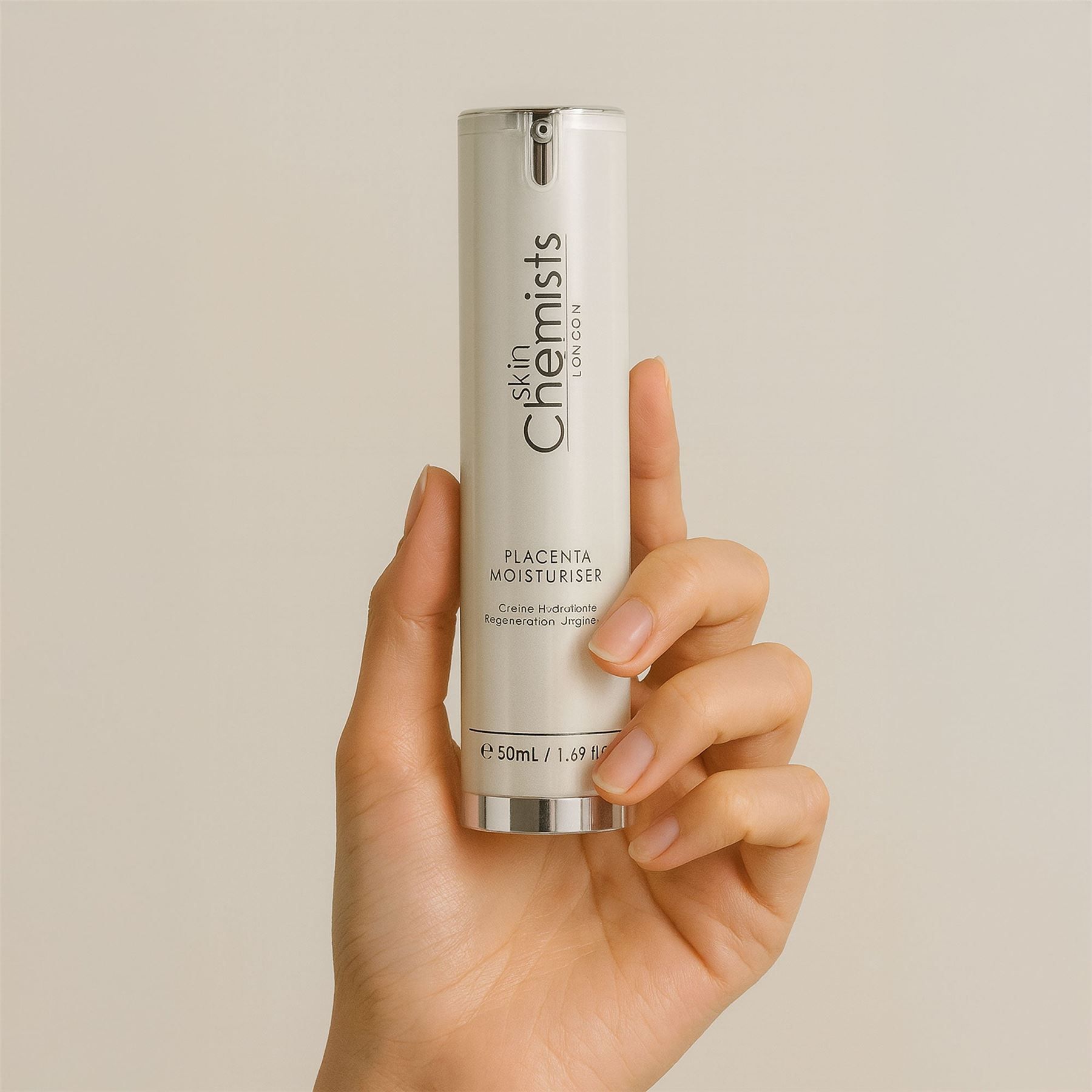Eine Hand hält einen silbernen Pumpspender der Skin Chemists Feuchtigkeitscreme.