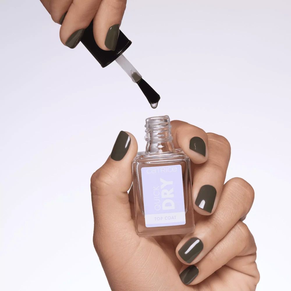 Hand hält Nagellackpinsel über Catrice Quick Dry Überlack-Flasche. Tropfen Nagellack.