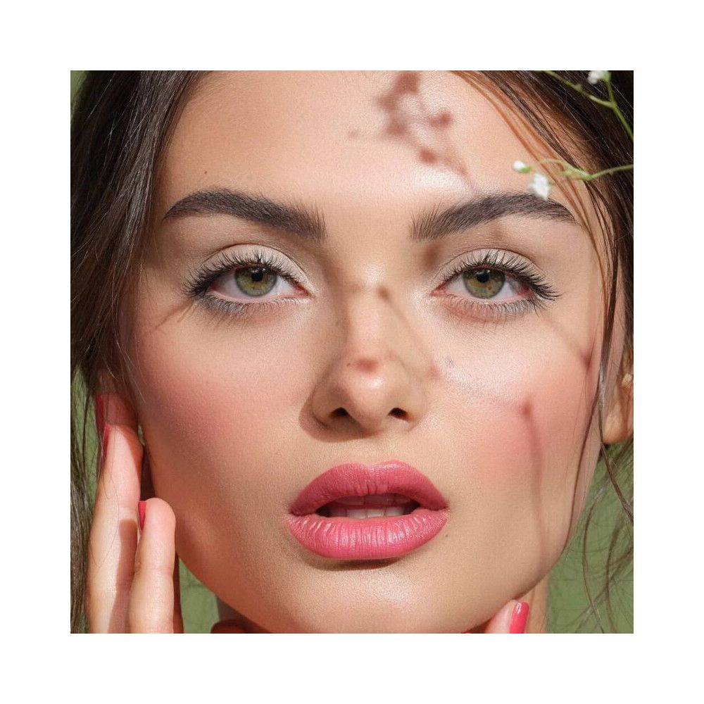 Nahaufnahme eines Gesichts mit Make-up. Fokus auf Augen und Lippen. Natürliche Beleuchtung. Zarte Blüten im Hintergrund.