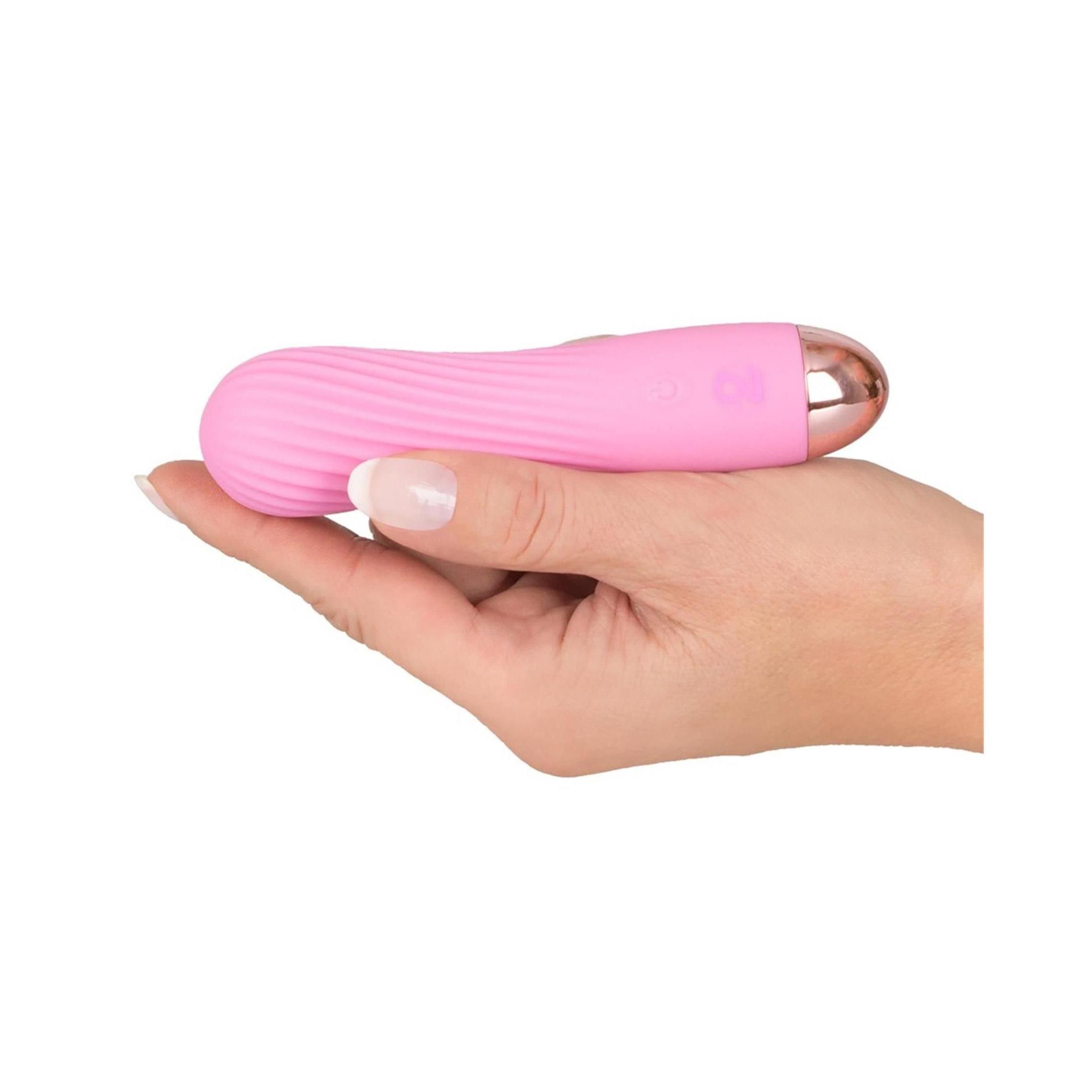 Rosa Vibrator in Hand gehalten. Goldfarbene Spitze, gewellte Oberfläche.