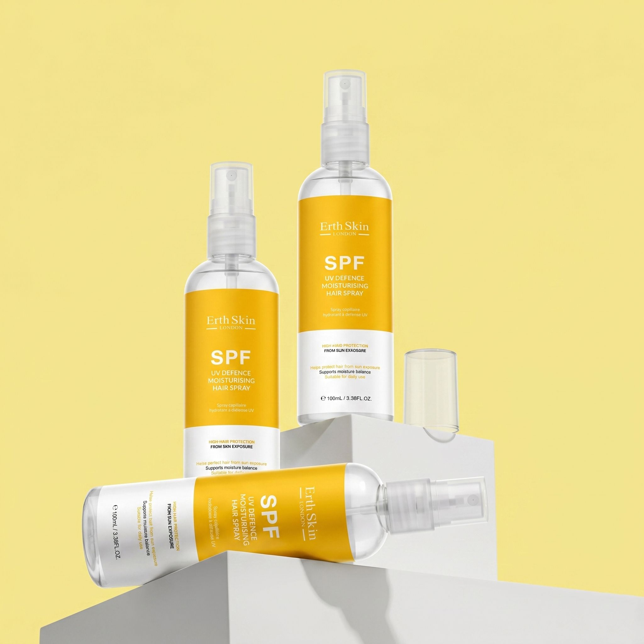 Mehrere Flaschen Haarspray mit gelben Etiketten. Aufschrift: SPF. Sprühköpfe. ErthSkin London.