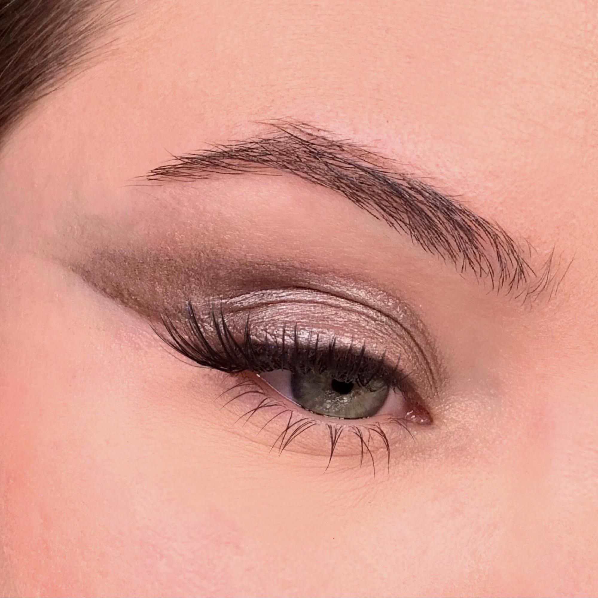 Nahaufnahme eines Auges mit Lidschatten und Eyeliner. Die Wimpern sind getuscht.