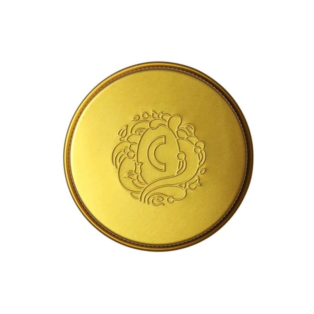 Goldener Deckel mit geprägtem Logo. Das Logo ist ein "C" in einem floralen Design.