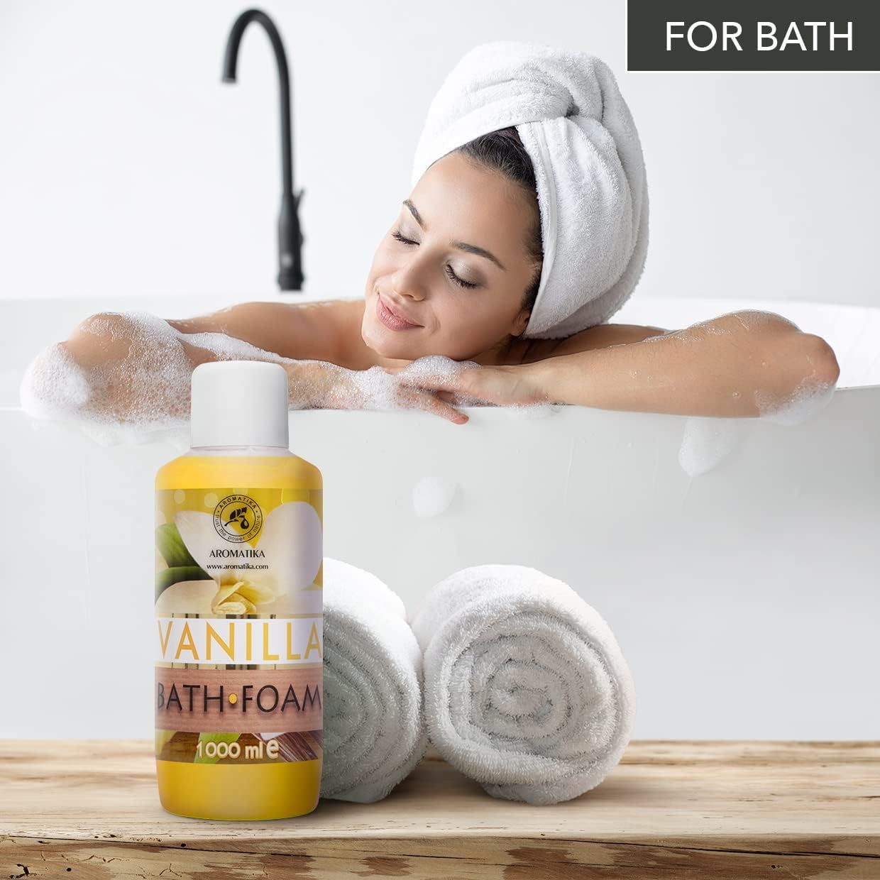 Gelbe Flasche mit weißem Deckel neben einer Frau in der Badewanne. Aufschrift: AROMATIKA, VANILLA BATH FOAM. Handtücher.