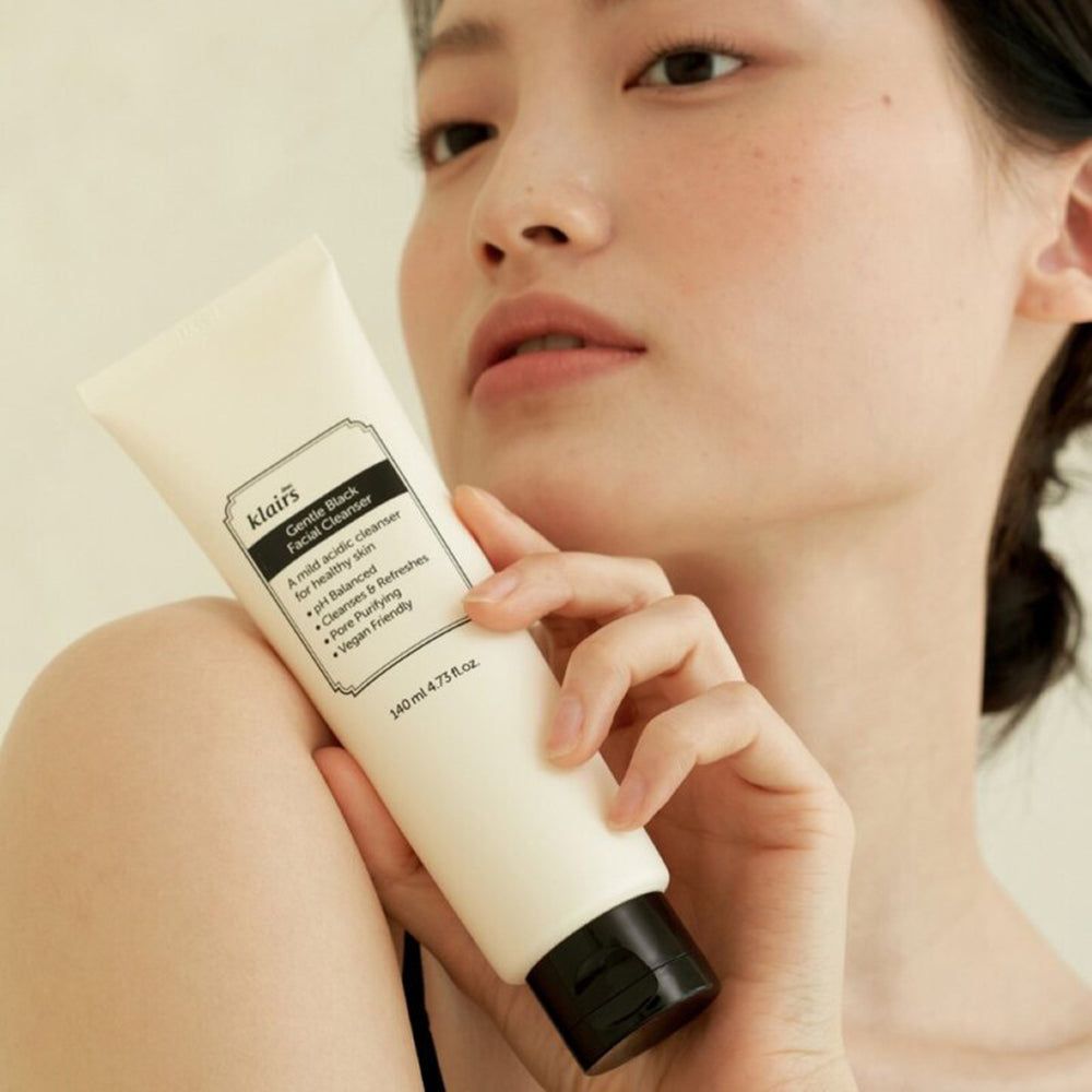 Frau hält eine Tube. Aufschrift: Gentle Black Facial Cleanser. Vegan. Hautpflegeprodukt.