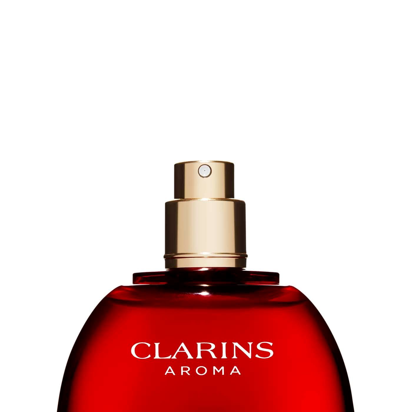 Nahaufnahme der roten Flasche Clarins Aroma. Goldener Sprühkopf. Weißer Verschluss. Auf weißem Hintergrund.