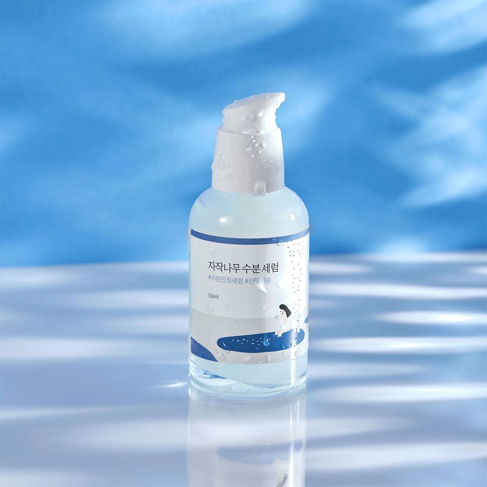 Round Lab Birch Juice Serum, 50ml, in Pumpspender auf blauem Hintergrund mit Lichtreflexen.
