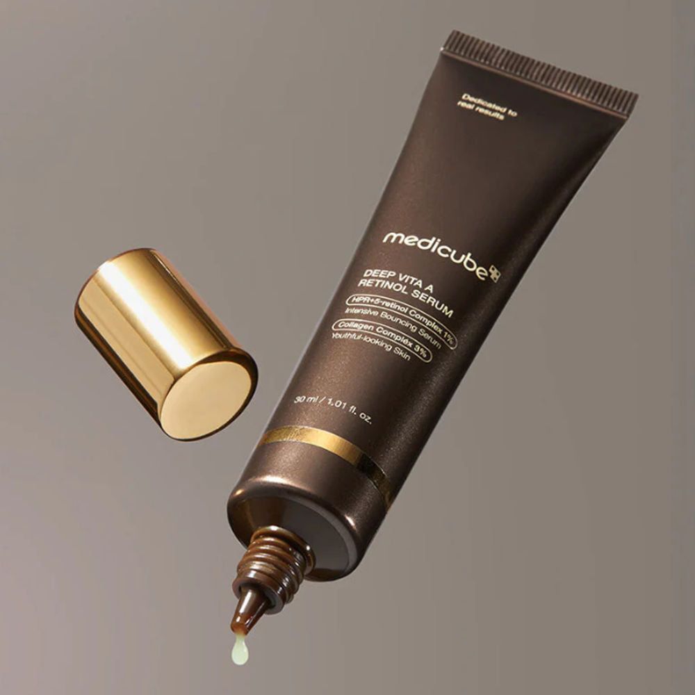 Braune Tube mit goldener Kappe. Produktname: Medicube Deep Vita A Retinol Serum. Tropfen Serum sichtbar.