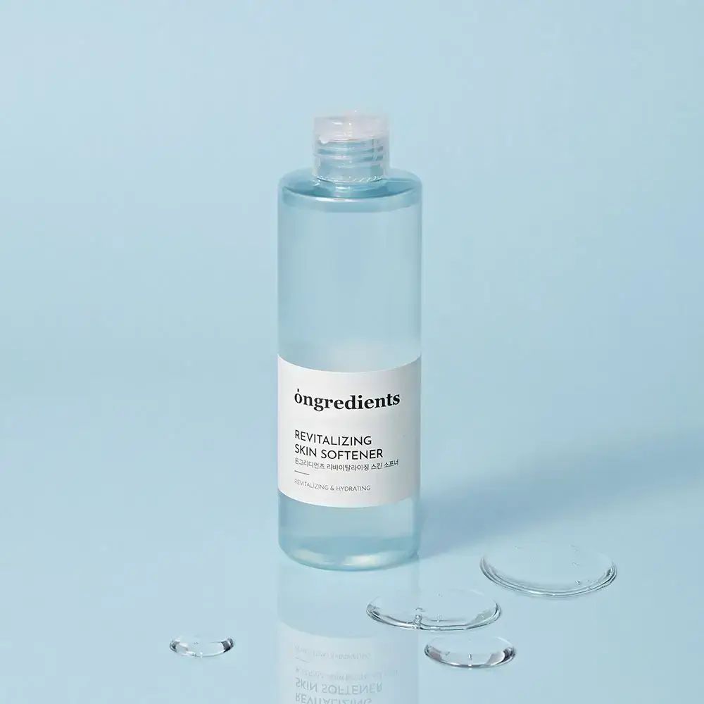 Transparente Flasche mit weißem Etikett und Wassertropfen. Aufschrift: Ongredients, Revitalizing Skin Softener. Klare Flüssigkeit.