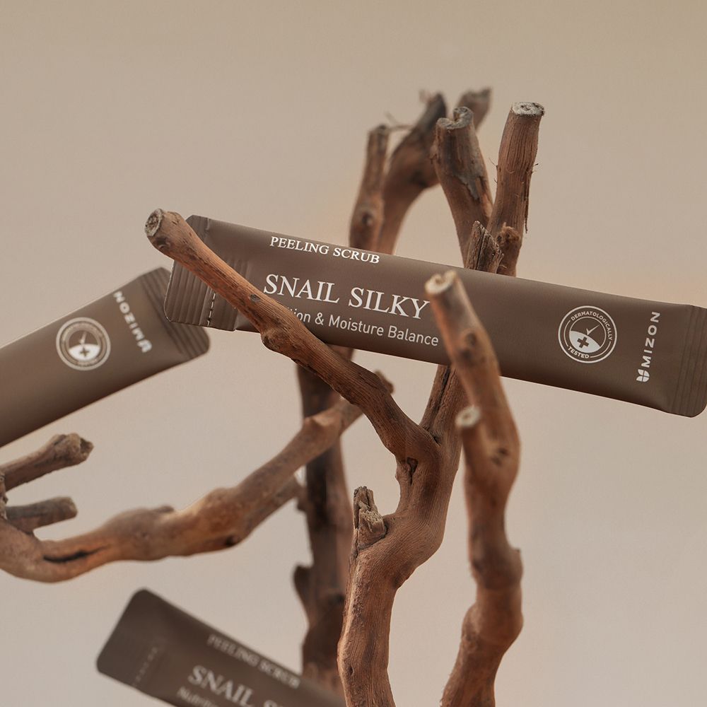 Produktbeutel auf Ästen. Aufschrift: Snail Silky, MIZON. Braune Verpackung.
