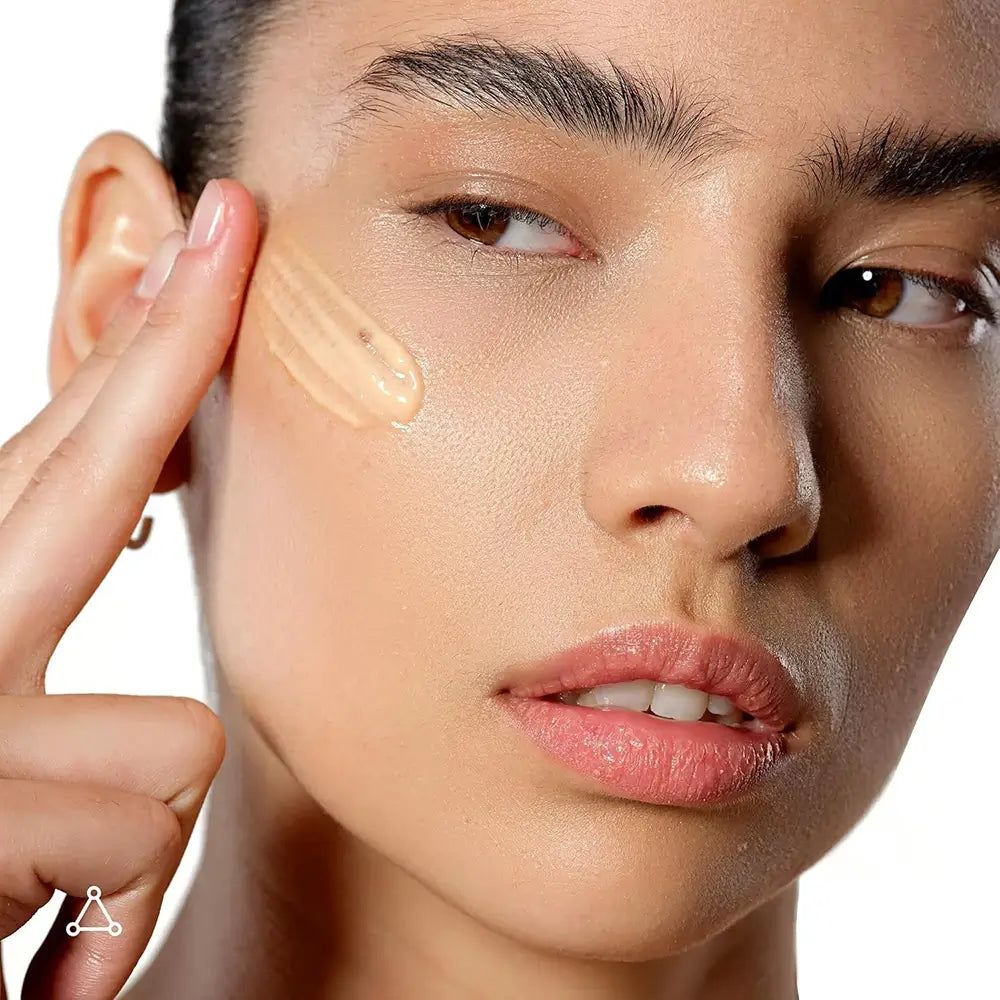 Frau trägt Creme auf. Creme-Tropfen auf der Haut. Marke nicht sichtbar.