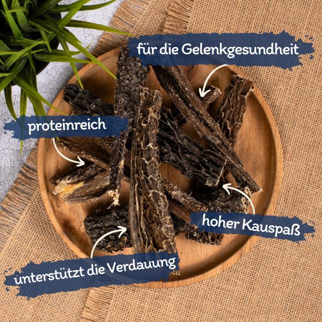Rinderpansenstücke auf Holzplatte. Text: proteinreich, für die Gelenkgesundheit, hoher Kauspaß, unterstützt die Verdauung.