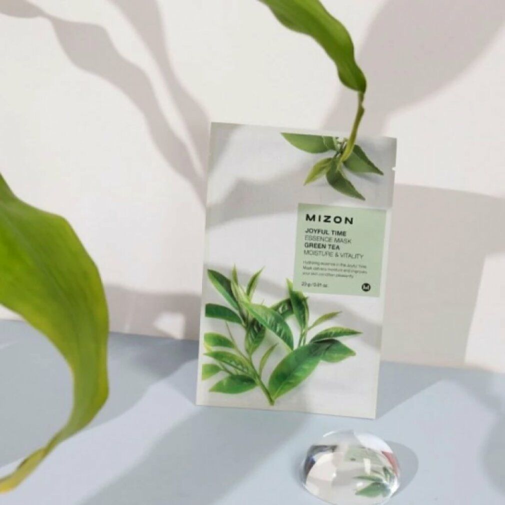 Verpackung der MIZON Joyful Time Essence Mask Green Tea. Produktverpackung mit grünen Blättern und einem dekorativen Objekt.